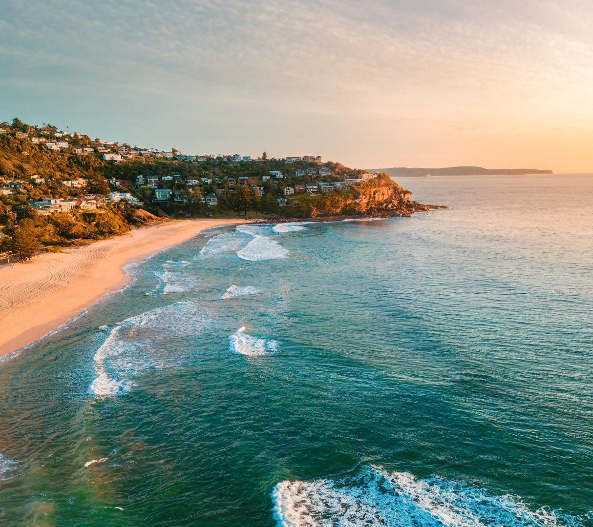 Aerial view of a Northern Beaches beach and headland at sunset