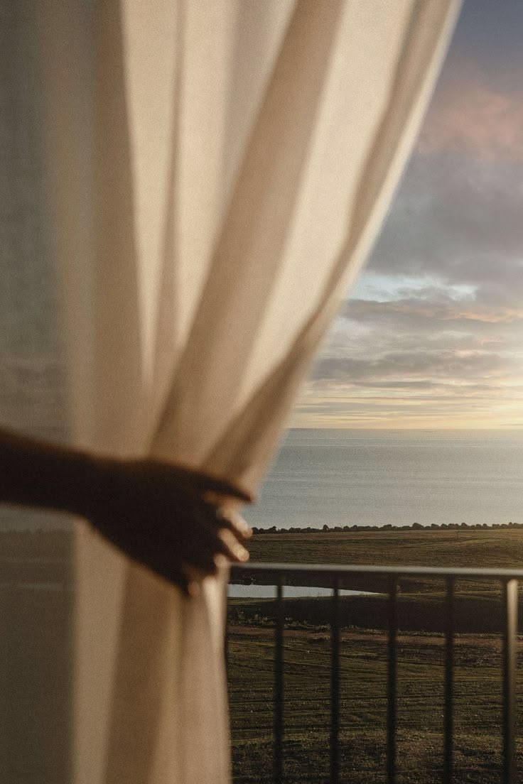 Ocean view through a curtained window